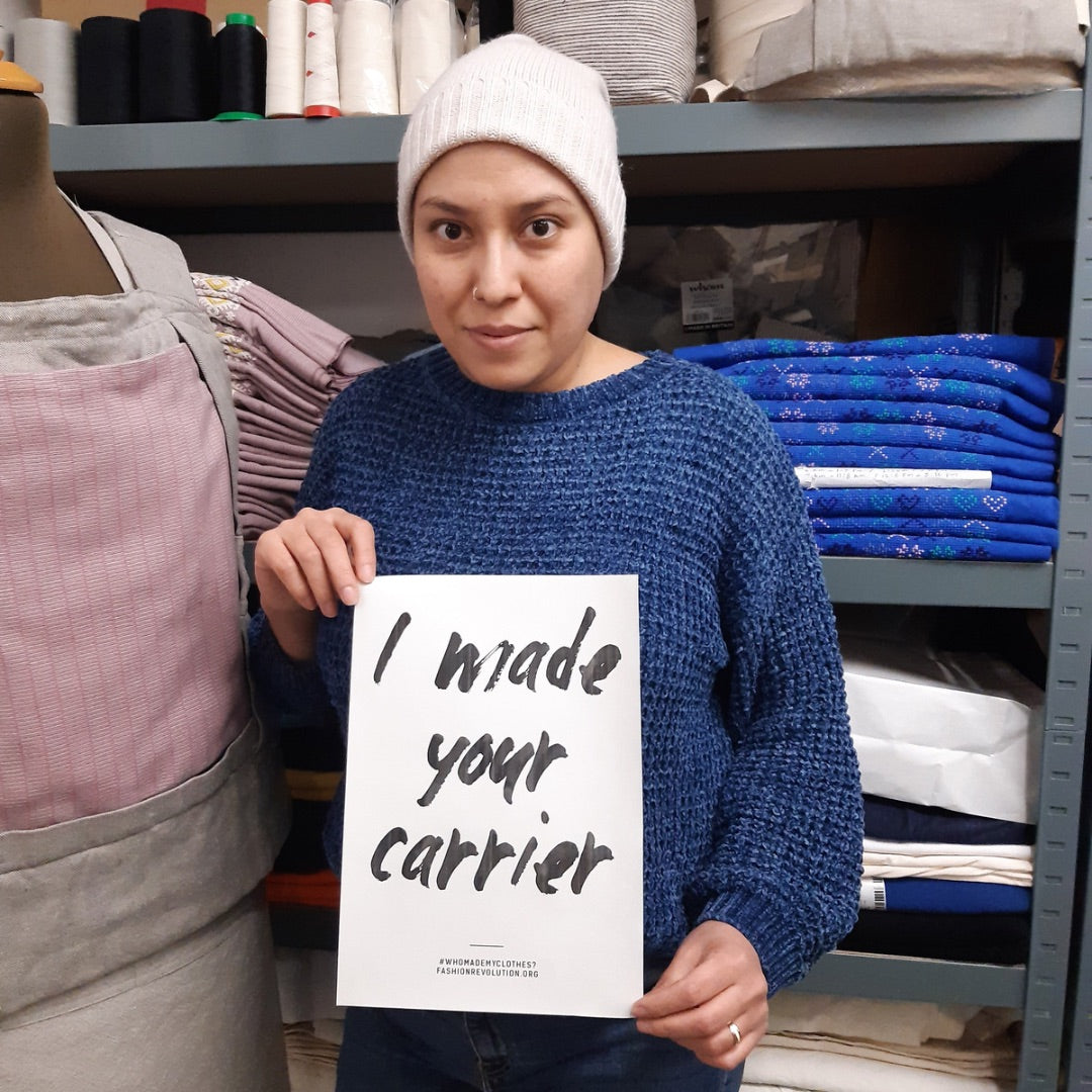 A seamstress holding an „I made your carrier“ sign